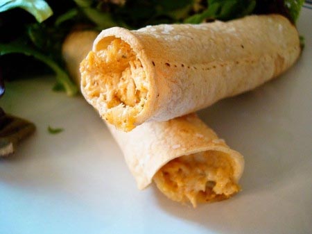 Two chicken taquitos on a white plate.