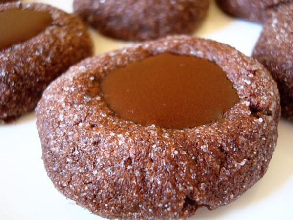 Chocolate thumbprint cookies filled with chocolate ganache on a white plate.