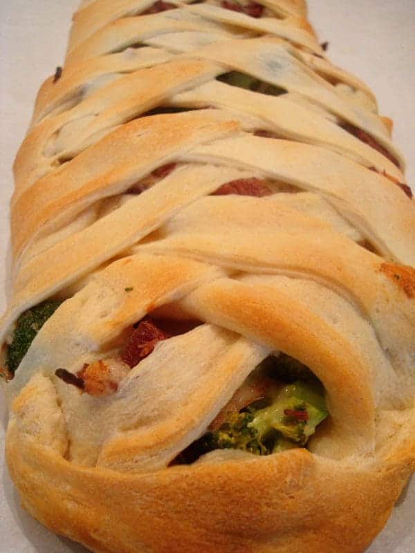 Bread with crisscrossed top filled with broccoli and ham.