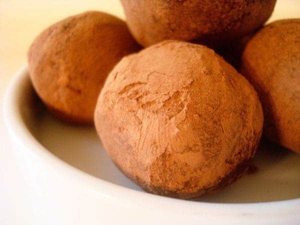 Chocolate dusted truffles on a white plate.