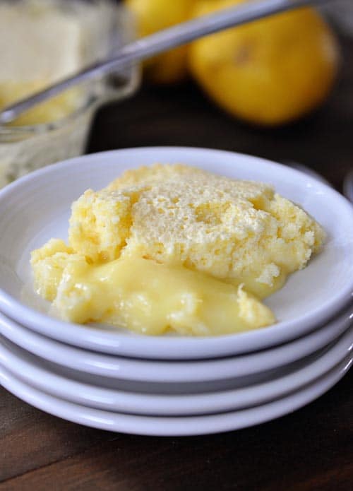 Lemon pudding cake on a stack of white plates.