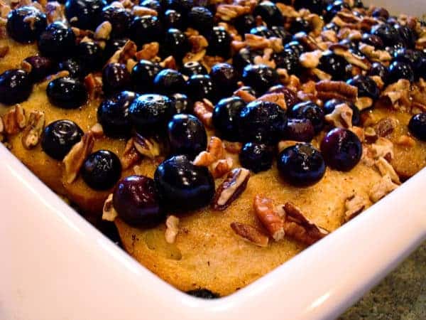 White dish with baked french toast topped with blueberries.