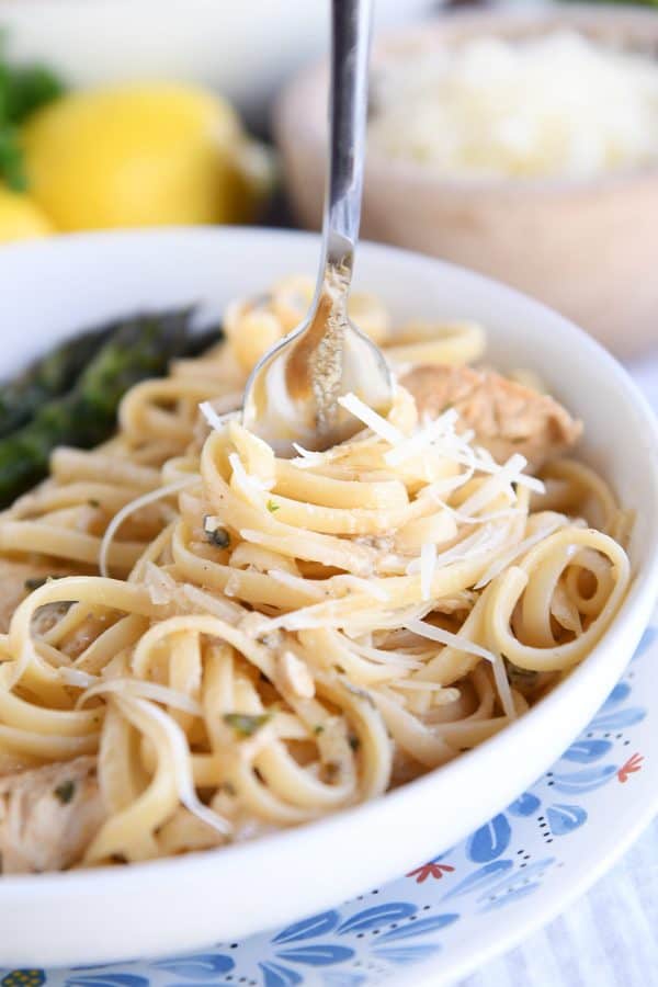Twisting pasta in white dish around fork.