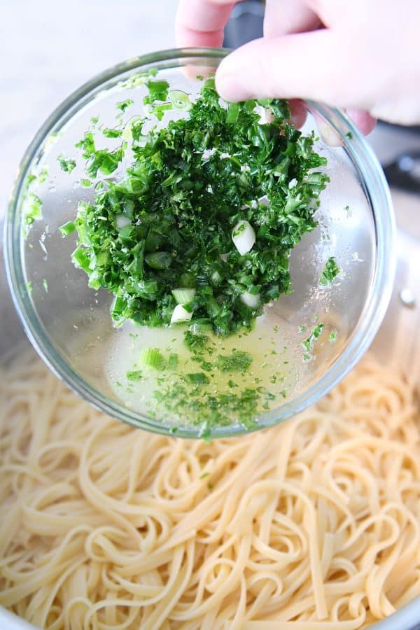 Adding green onions and lemon juice to cooked linguine.