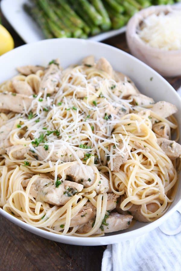 Tossed lemon chicken pasta in white bowl with Parmesan cheese.