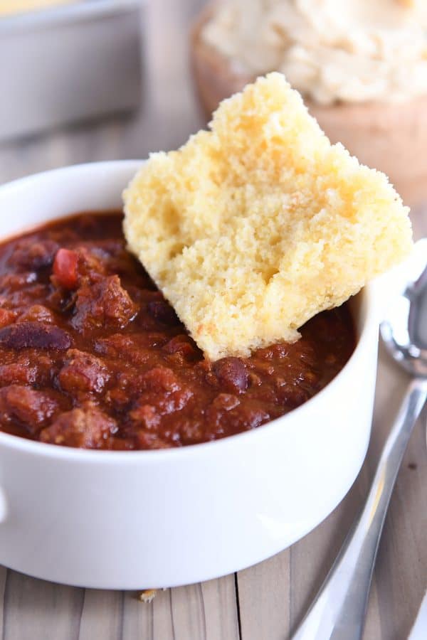 Piece of cornbread on the side of the bowl of chili.