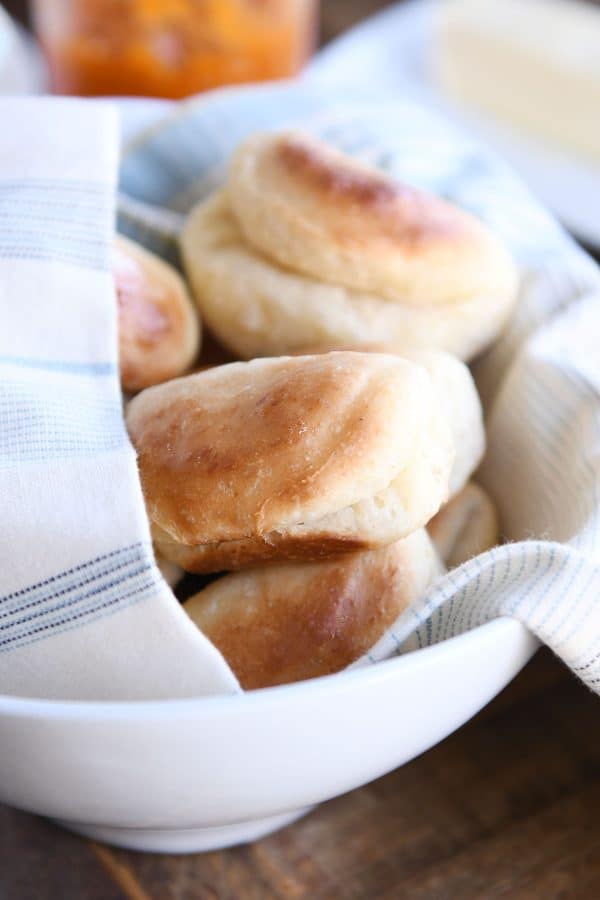 Baked fluffy 2-hour Parker house rolls in basket with towel.