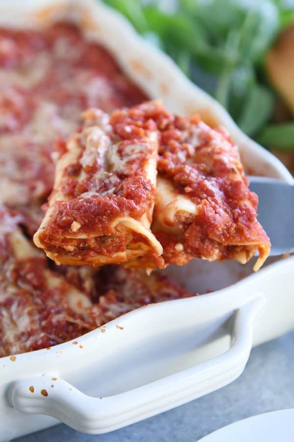 two baked manicotti on metal spatula