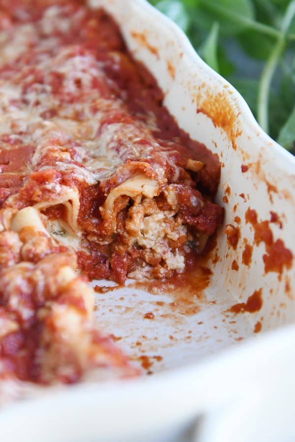 Ceramic pan with baked manicotti and red sauce.