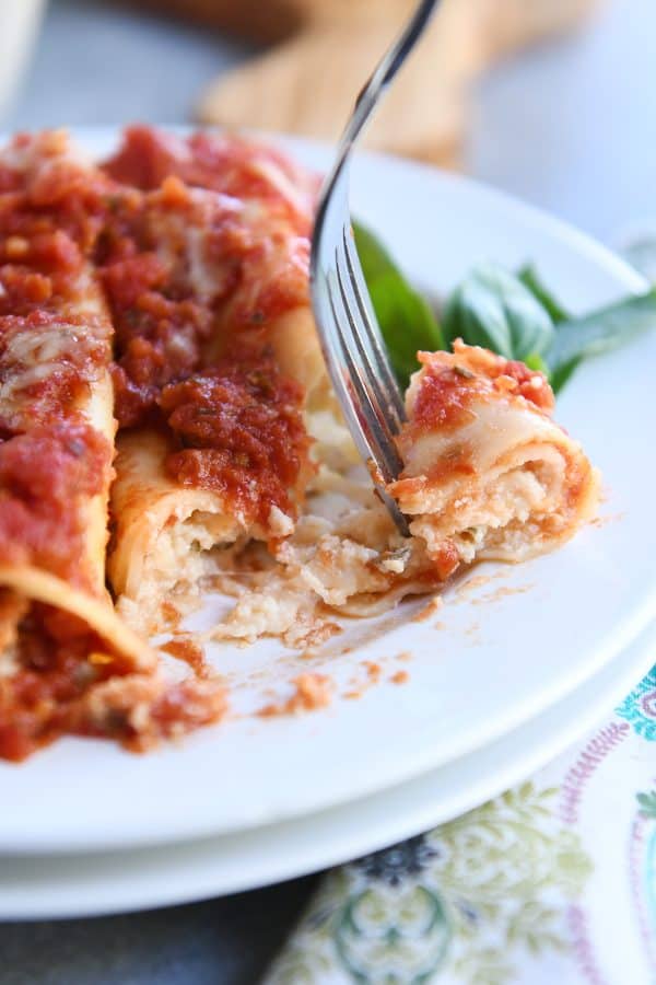 Taking bite out of best baked manicotti with fork.