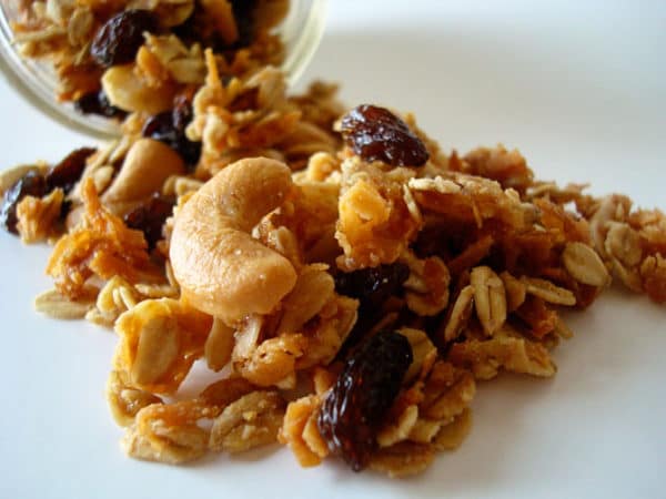 Cashew granola spilling out of a glass mason jar.