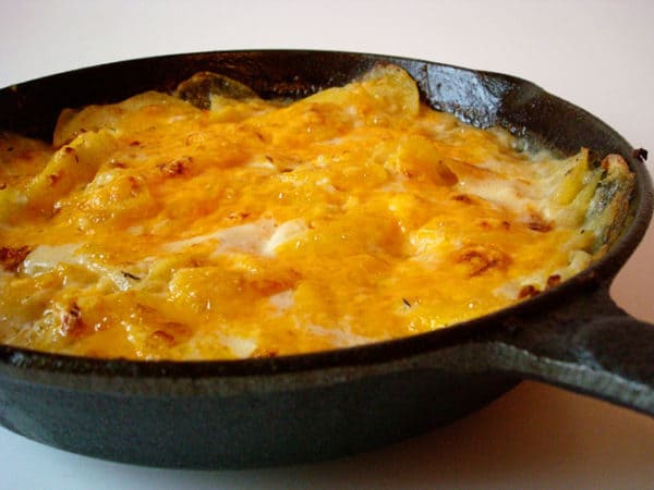 Skillet of scalloped potatoes and melted cheese.