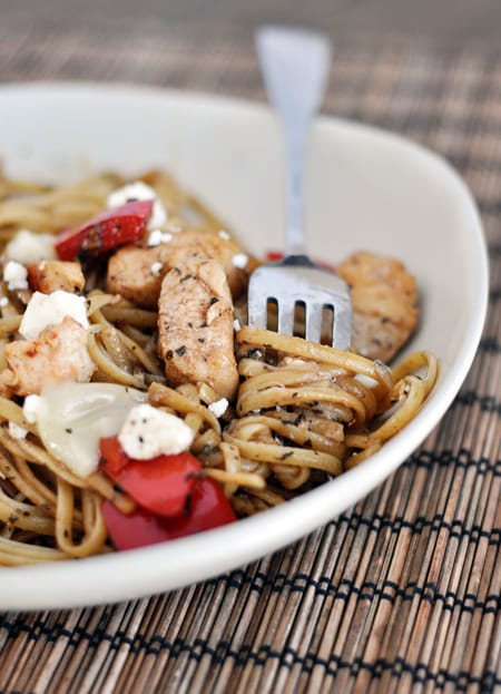 White bowl with cooked pasta, chicken, and red pepper.