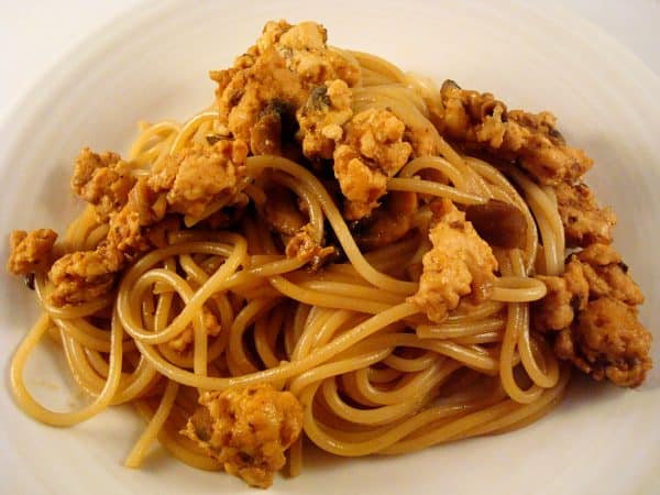 Top view of a white plate with cooked spaghetti noodles and meat.