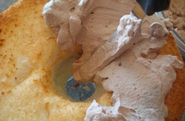 Angel Food Cake being frosted with chocolate frosting