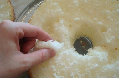pulling pieces out of the middle of a cut angel food cake