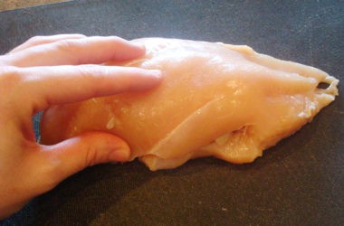 raw chicken breast on a black cutting board