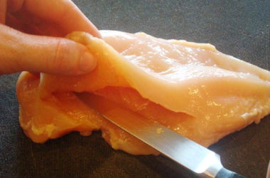 raw chicken breast being cut in half