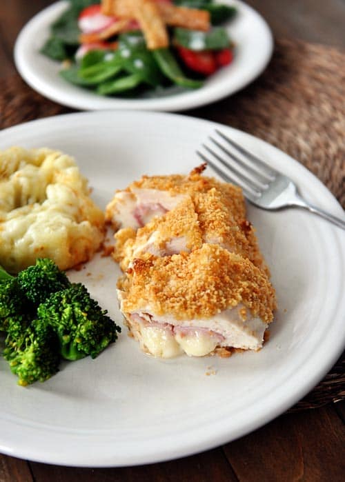 Chicken cordon bleu, broccoli, and potatoes on a white plate.