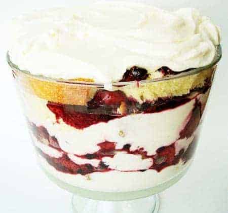 Layered lemon pound cake, berry, and whipped cream in a clear trifle dish.