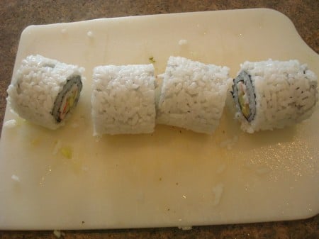 sushi roll cut in fourths on a white cutting board