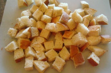 one inch bread cubes on a white cutting board