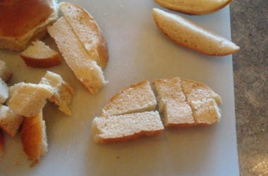 rolls being cut into cubes on a white cutting board