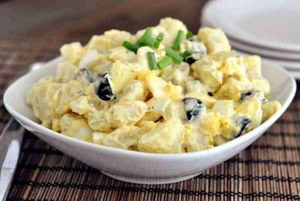 White bowl of classic potato salad topped with chives.