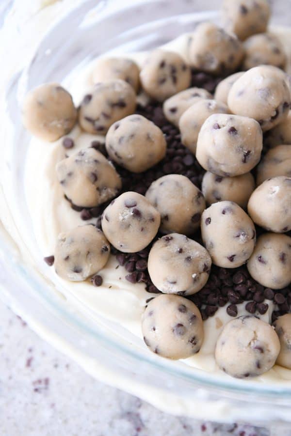 Cookie dough balls with mini chocolate chips and cheesecake batter in glass bowl.