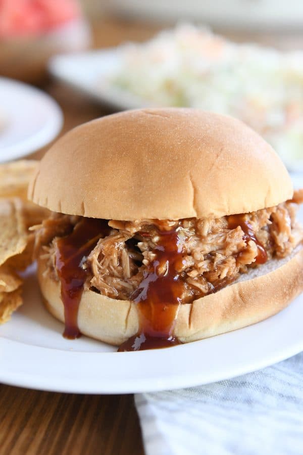 BBQ pork sandwich on bun on white plate.