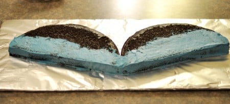 chocolate cake cut in half with the lower half frosted in blue