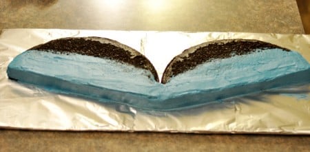 chocolate cake cut in half with the lower half of the cakes frosted in blue