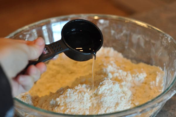 measuring cup adding water to a flour and butter mixture