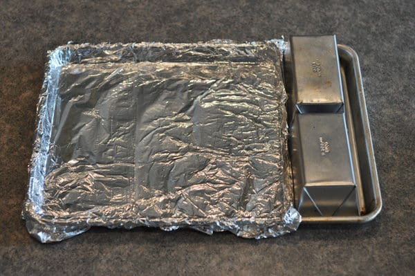 sheet pan covered in tinfoil, with two small bread pans on the side