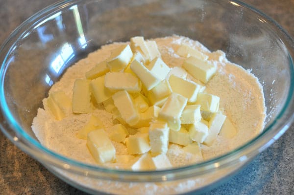 cubed butter on flour in a glass bowl