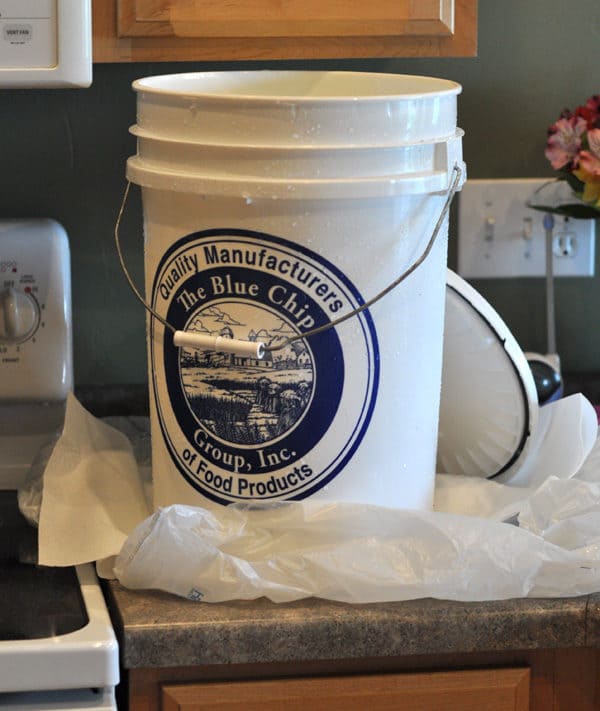 white five gallon bucket on a countertop with the lid next to it
