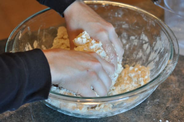 hands mixing dough in a glass bowl
