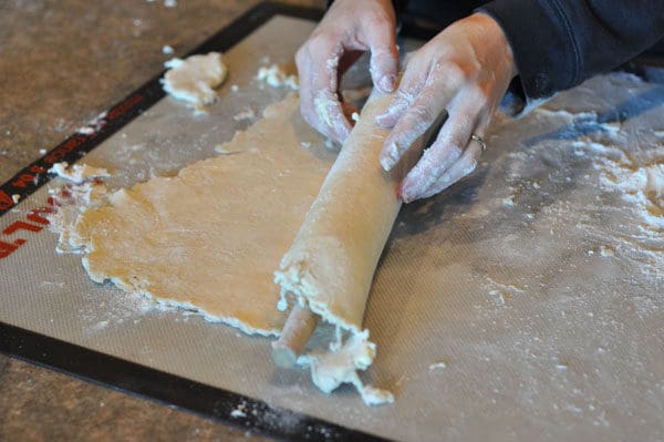 rolling up a pie crust over a rolling pin