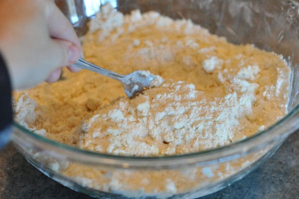 fork mixing water and dough mixture together in a glass bowl
