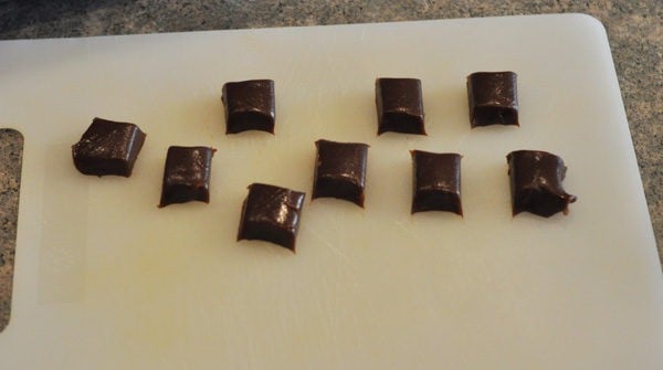 small squares of chocolate caramels on a white cutting board