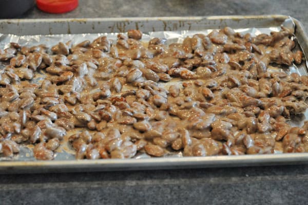 candy coated almonds spread out on a tinfoil lined cookie sheet