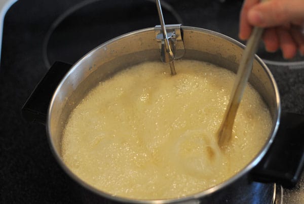 butter and sugar mixture boiling and being stirred by a wooden spoon