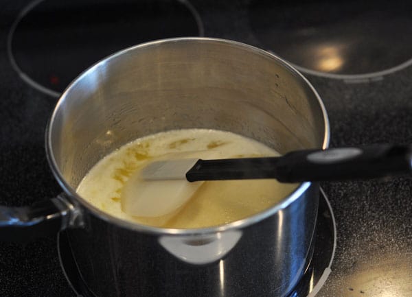 Pot of melting butter with a rubber spatula in it.