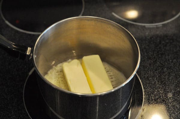 two sticks of butter melting in a saucepan