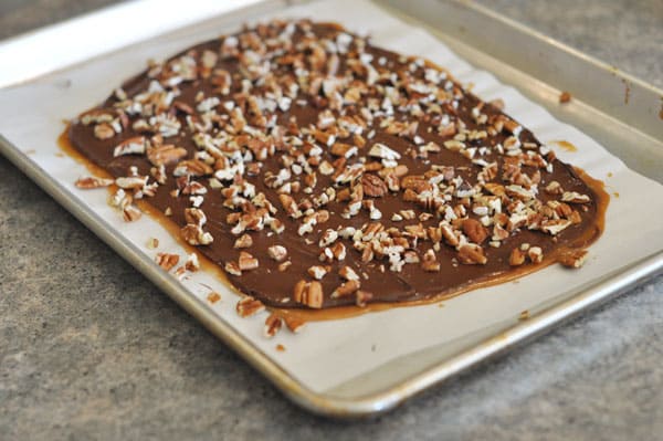 Chocolate and pecan topped toffee in a big slab on a cookie sheet.
