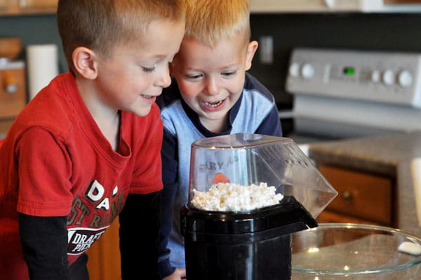 two little boys looking happily at popcorn popping in a popcorn maker