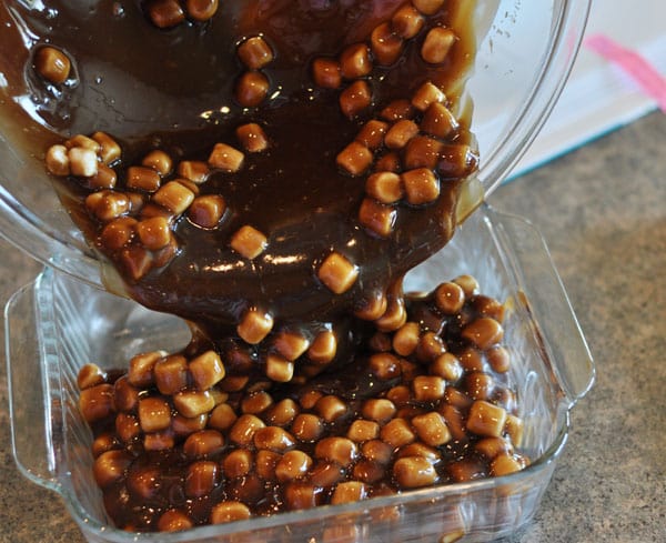 marshmallow studded fudge being poured into a glass 8x8 pan