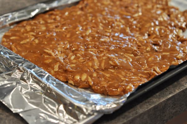 caramel coated almonds spread out on a tinfoil lined sheet pan