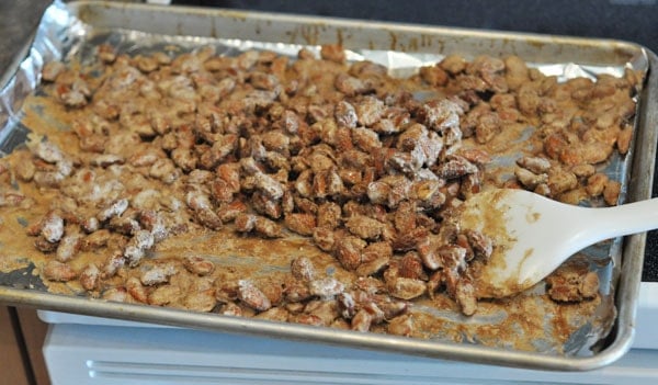 candy coated almonds on a cookie sheet that have been baking until golden brown