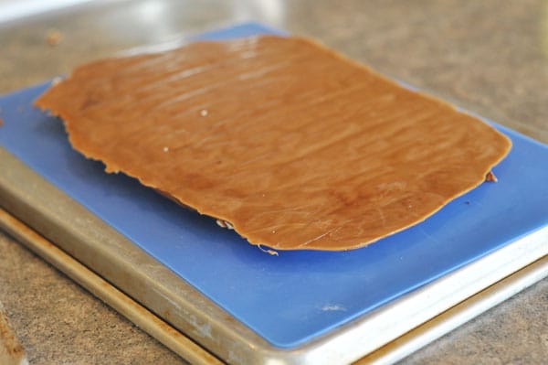 big slab of toffee turned upside down on a blue parchment liner